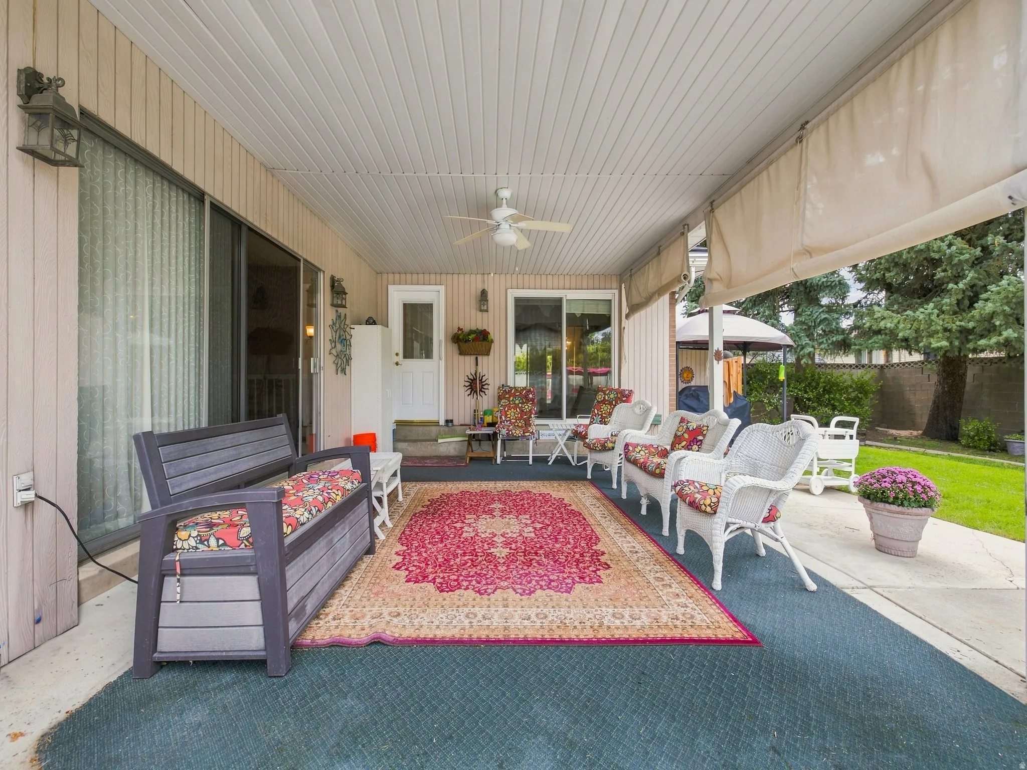 Covered patio with a paneled ceiling, ceiling fan, and outdoor lighting