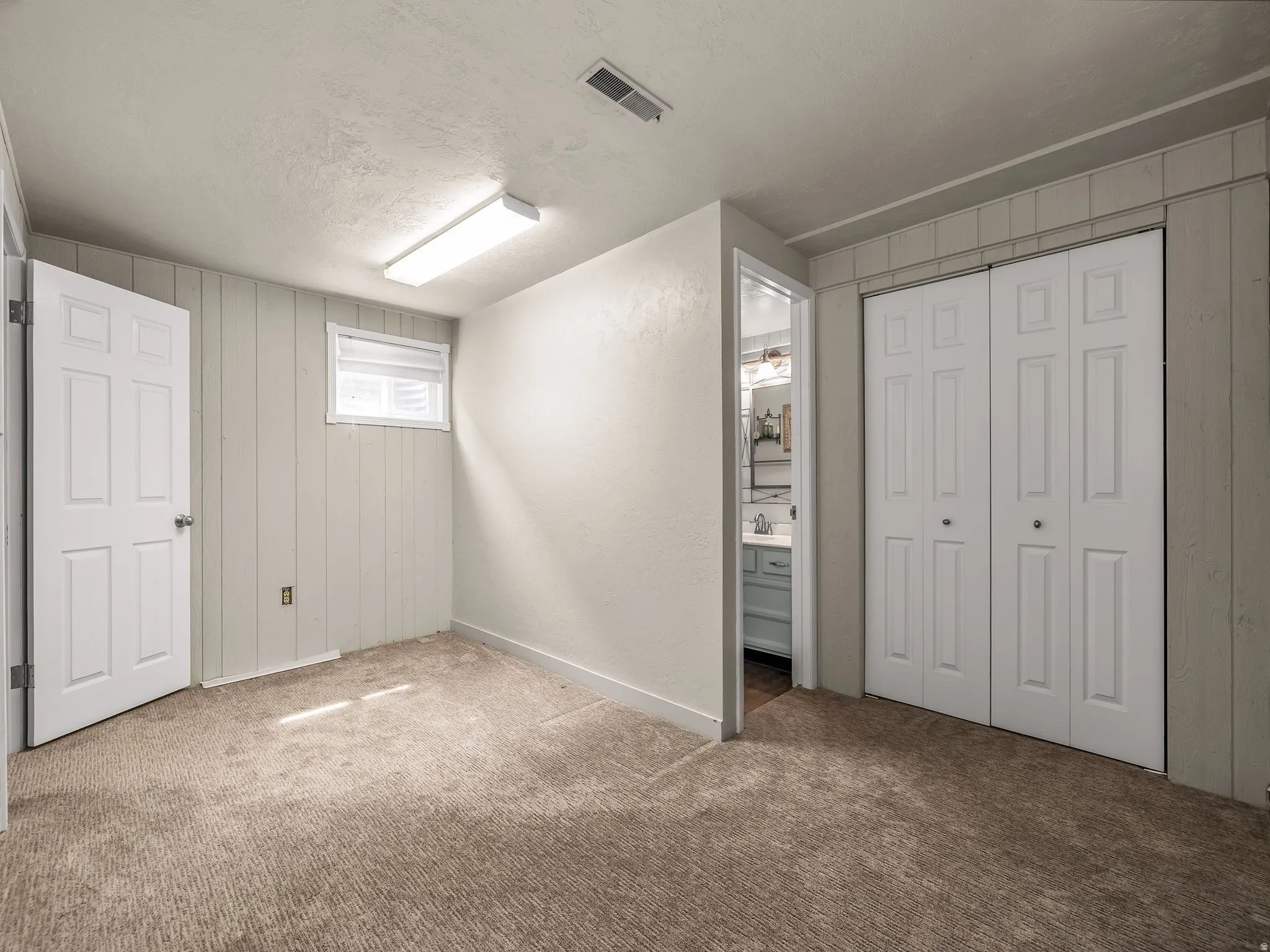Carpeted room with a window, single door, bi-fold closet doors, and recessed lighting