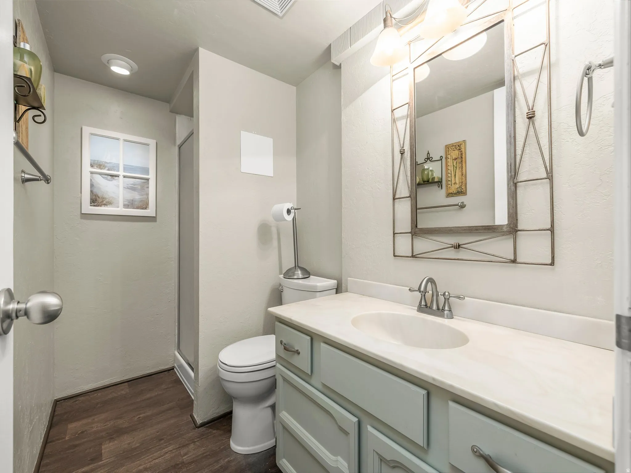 Wood-finish flooring with a vanity featuring a light-colored countertop and integrated sink
