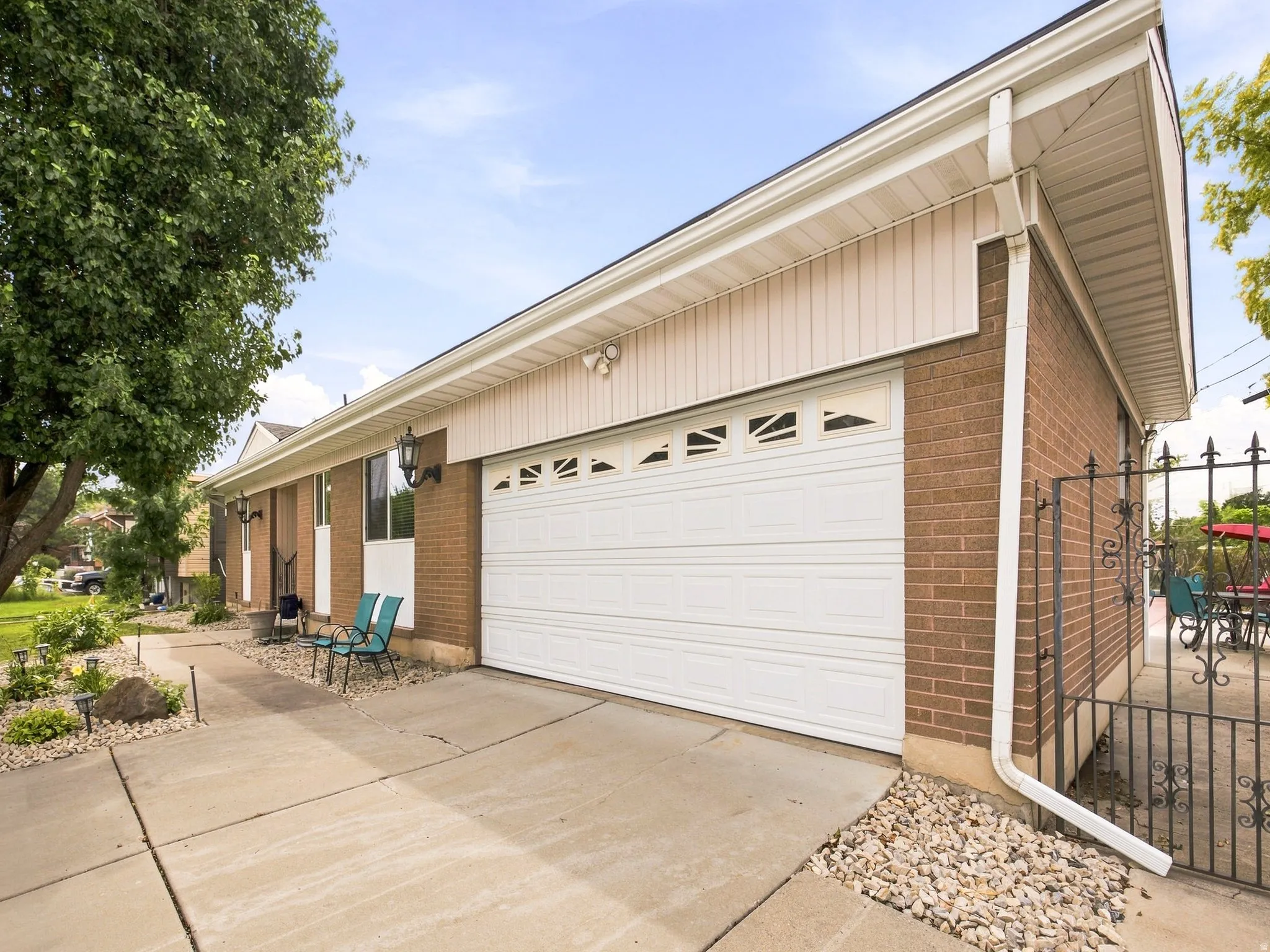 Attached two-car garage with overhead lighting, brick exterior, and a wrought iron side gate