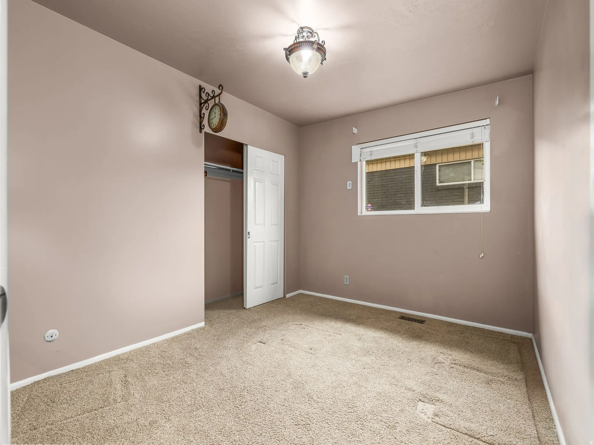Carpeted flooring, window with blinds, bi-fold closet door, and ceiling-mounted light fixture