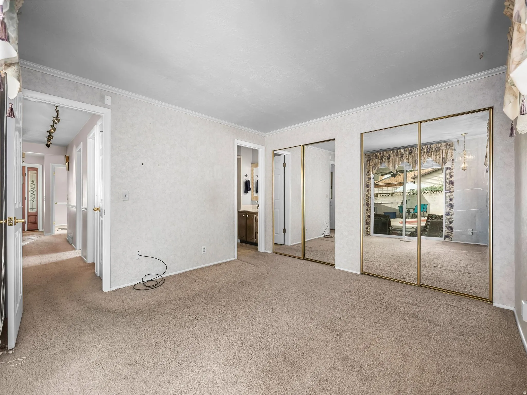 Carpeted flooring, mirrored sliding closet doors, and crown molding