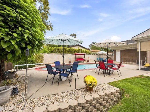 Expansive backyard featuring a built-in swimming pool, concrete patio, and a retaining wall