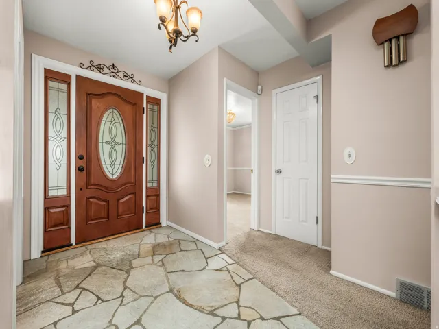 Wood-paneled entry door with decorative glass inserts and sidelights