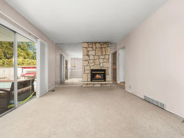 Stone-clad fireplace, large sliding glass doors, and light-toned carpeting throughout