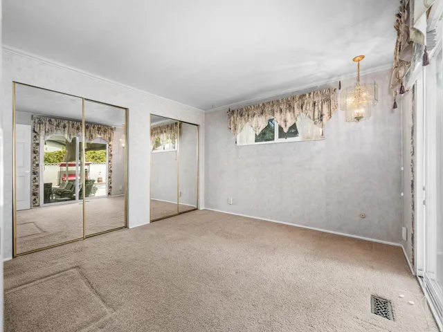 Spacious primary bedroom featuring mirrored sliding closet doors, neutral carpeting, and abundant natural light from dual windows