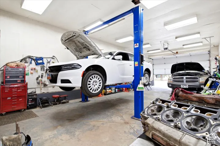 Concrete flooring, overhead fluorescent lighting, two vehicle bay doors, and a two-post vehicle lift