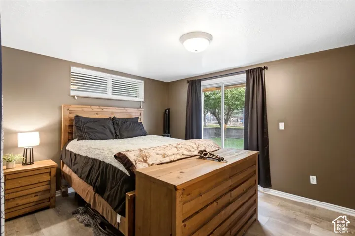 Light wood-finish flooring, sliding glass door with exterior access, horizontal window blinds, and overhead flush-mount lighting