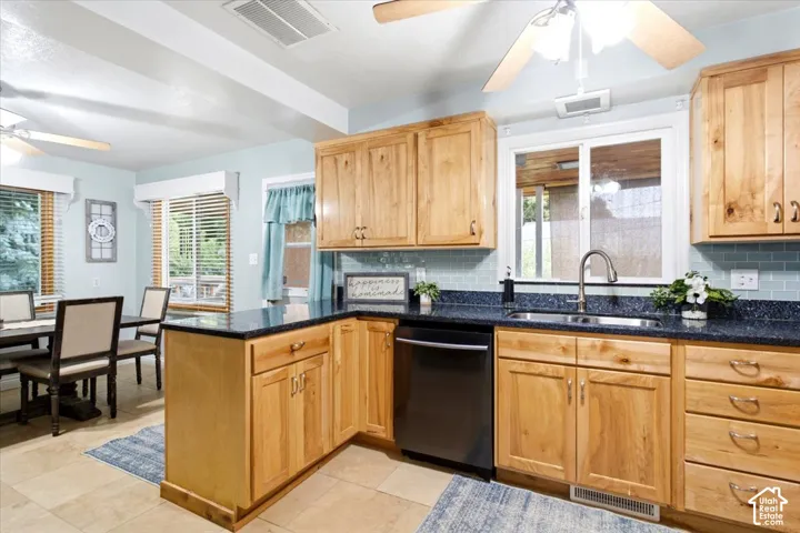 Wood-finish cabinetry, dark countertops, a tiled backsplash, and stainless steel appliances complete this kitchen space