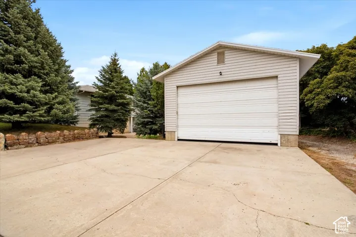 Detached garage with horizontal siding, a white garage door, and a concrete driveway