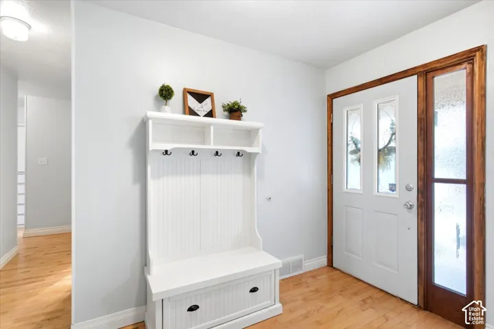 Entryway with wood-finish flooring, white door with decorative glass inserts, and a built-in hall tree with storage and hooks