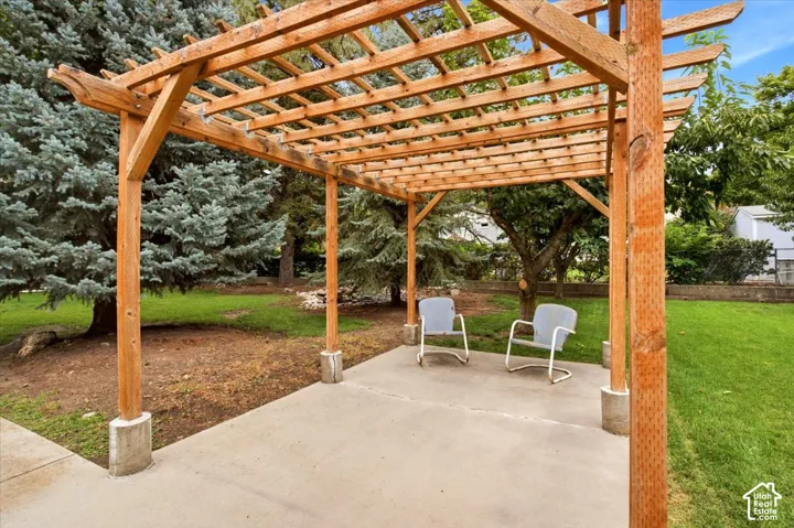 Striking wood-frame pergola with lattice overhead, anchored by substantial timber posts and concrete footings