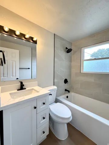 White vanity with a rectangular basin sink, black faucet, and white countertop