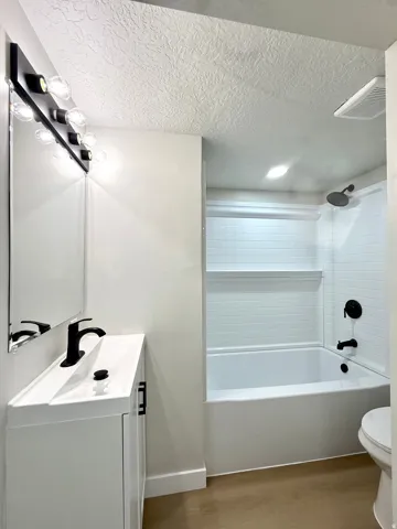 White vanity with integrated sink, black faucet, and rectangular mirror