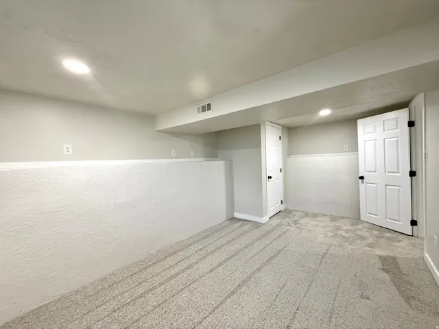 Recessed lighting, light gray carpet, white six-panel doors, white trim, and light gray walls