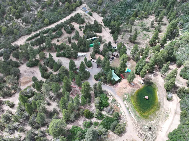 Expansive property featuring dense tree coverage, a private pond, and multiple structures