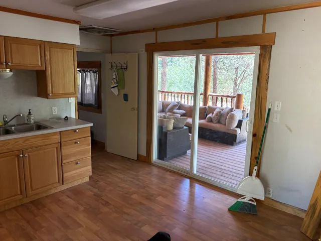 Kitchen area with wood-finish flooring, light wood cabinetry, and a double basin stainless steel sink