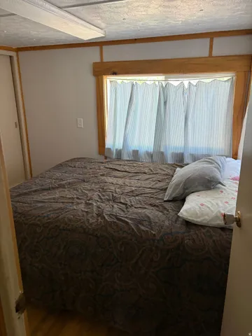 Wood-finish flooring with a window featuring wood trim, and a built-in wall light fixture