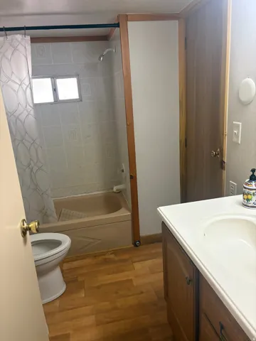 Bathroom featuring a built-in tub with tile surround, wood-finish flooring, and a vanity with an integrated sink
