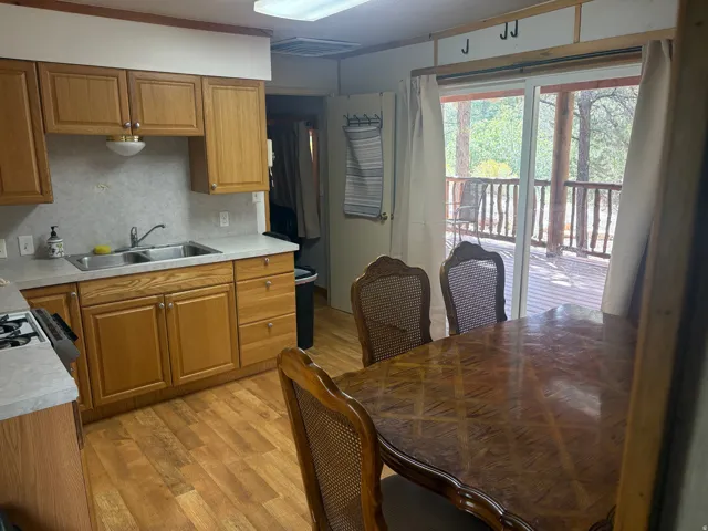 Kitchen area featuring wood-finish flooring, wood cabinetry, a double basin stainless steel sink, and light-colored countertops