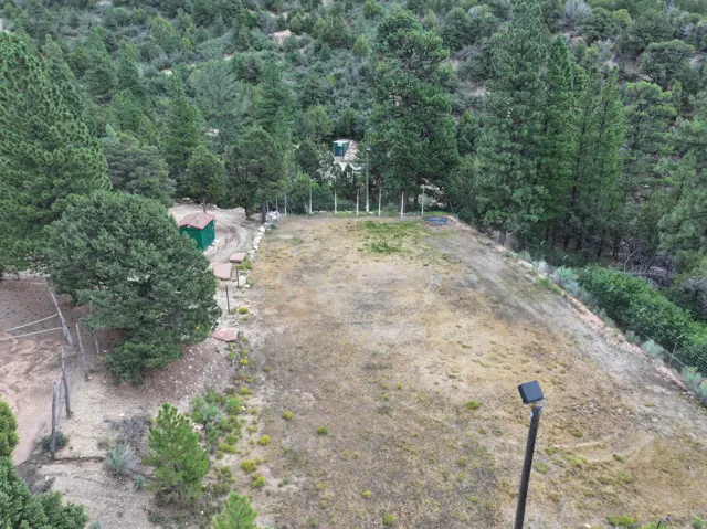 Expansive undeveloped lot with natural landscaping, mature trees, a small storage shed, and perimeter fencing