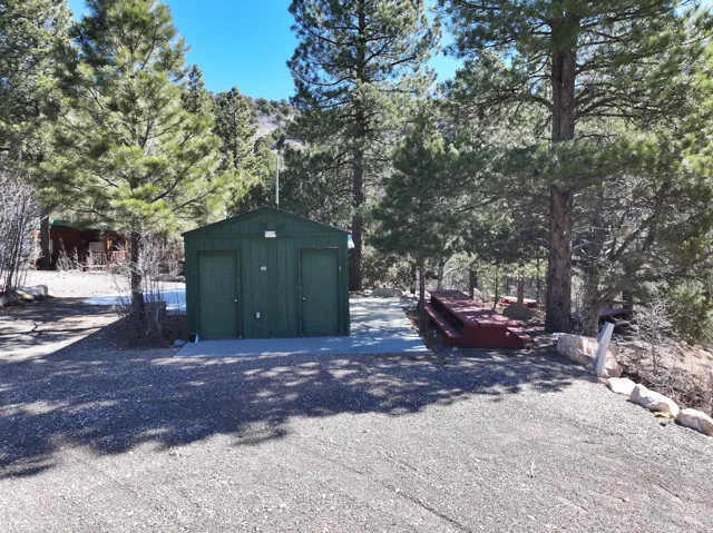 Gravel driveway with a green utility building and concrete pad