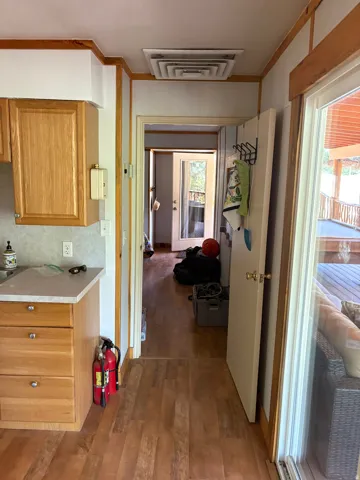 Wood-finish flooring throughout, light wood cabinetry, and a sliding glass door leading to an outdoor deck