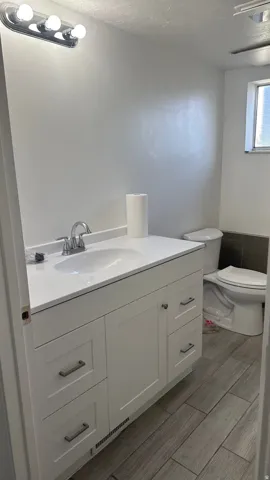 White vanity with shaker-style cabinetry, a single basin sink, and a chrome faucet