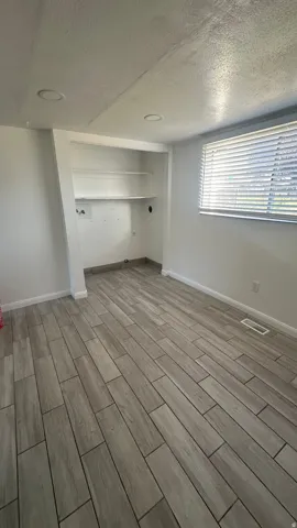 Recessed lighting, window with blinds, built-in shelving, and wood-look tile flooring
