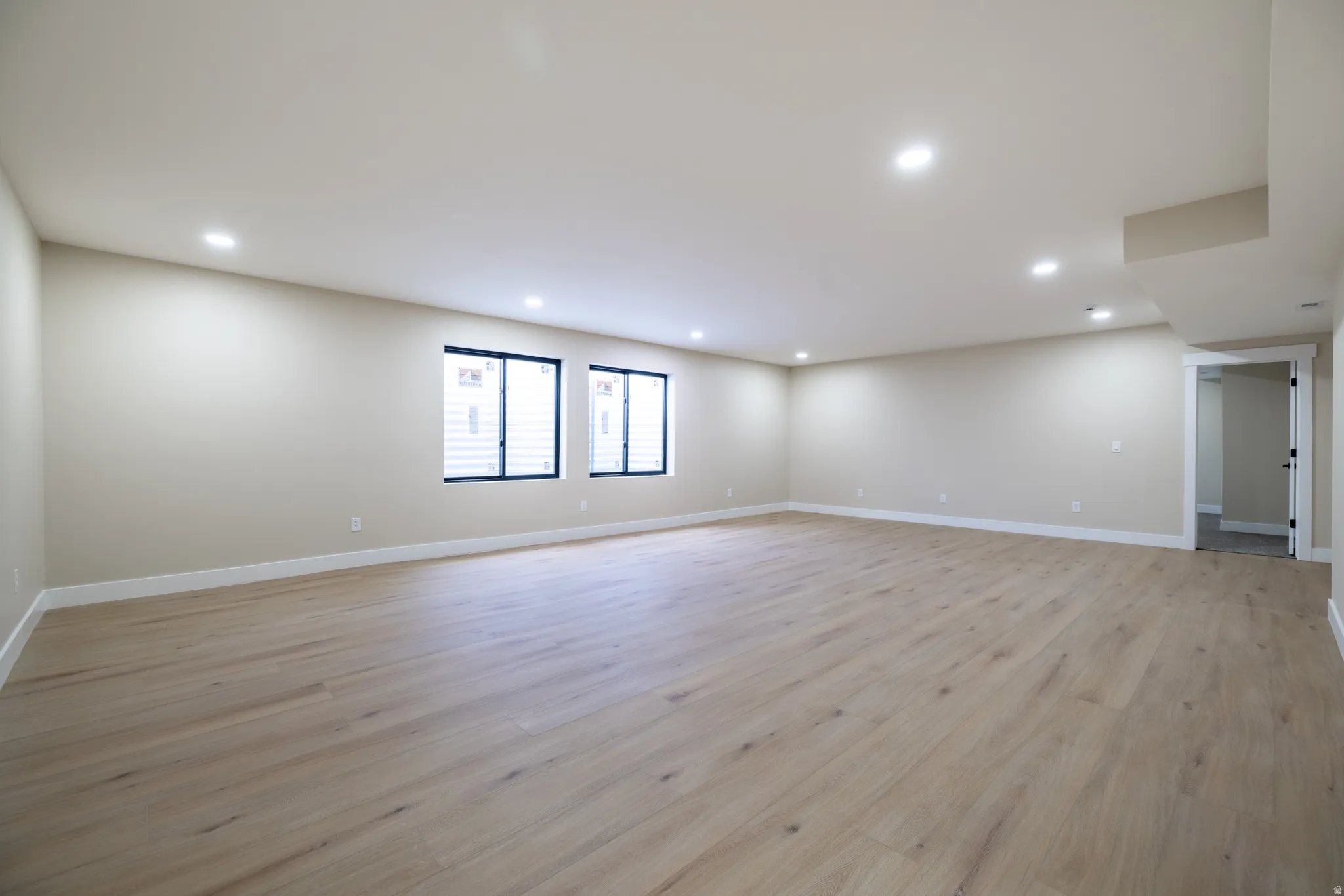 Spacious room featuring light wood-finish flooring, recessed lighting, and light-toned walls