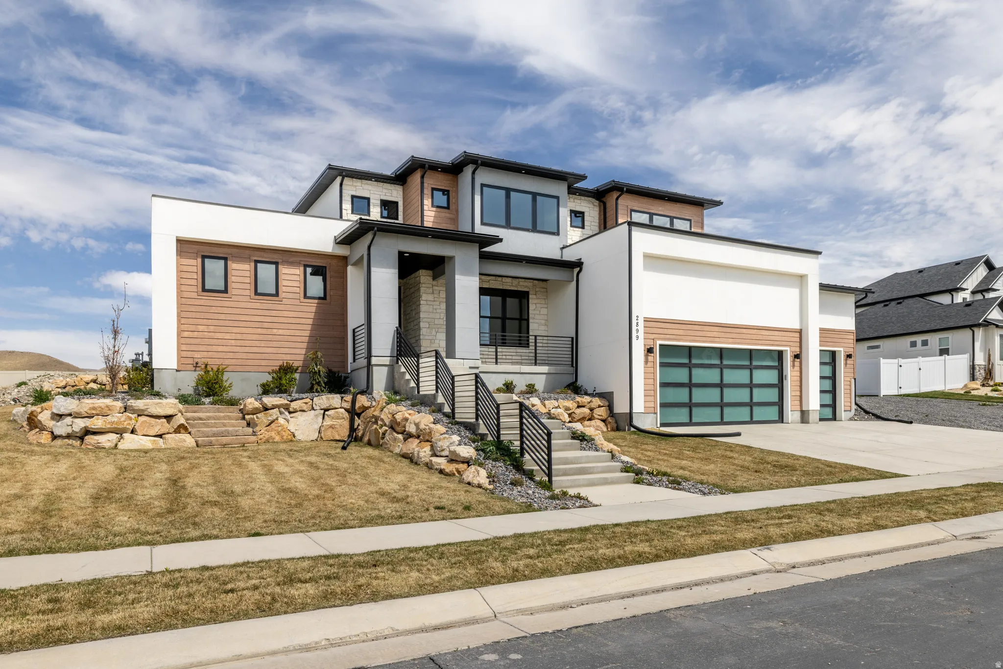 Modern exterior with varied siding, a glass-paneled garage door, and stone accents