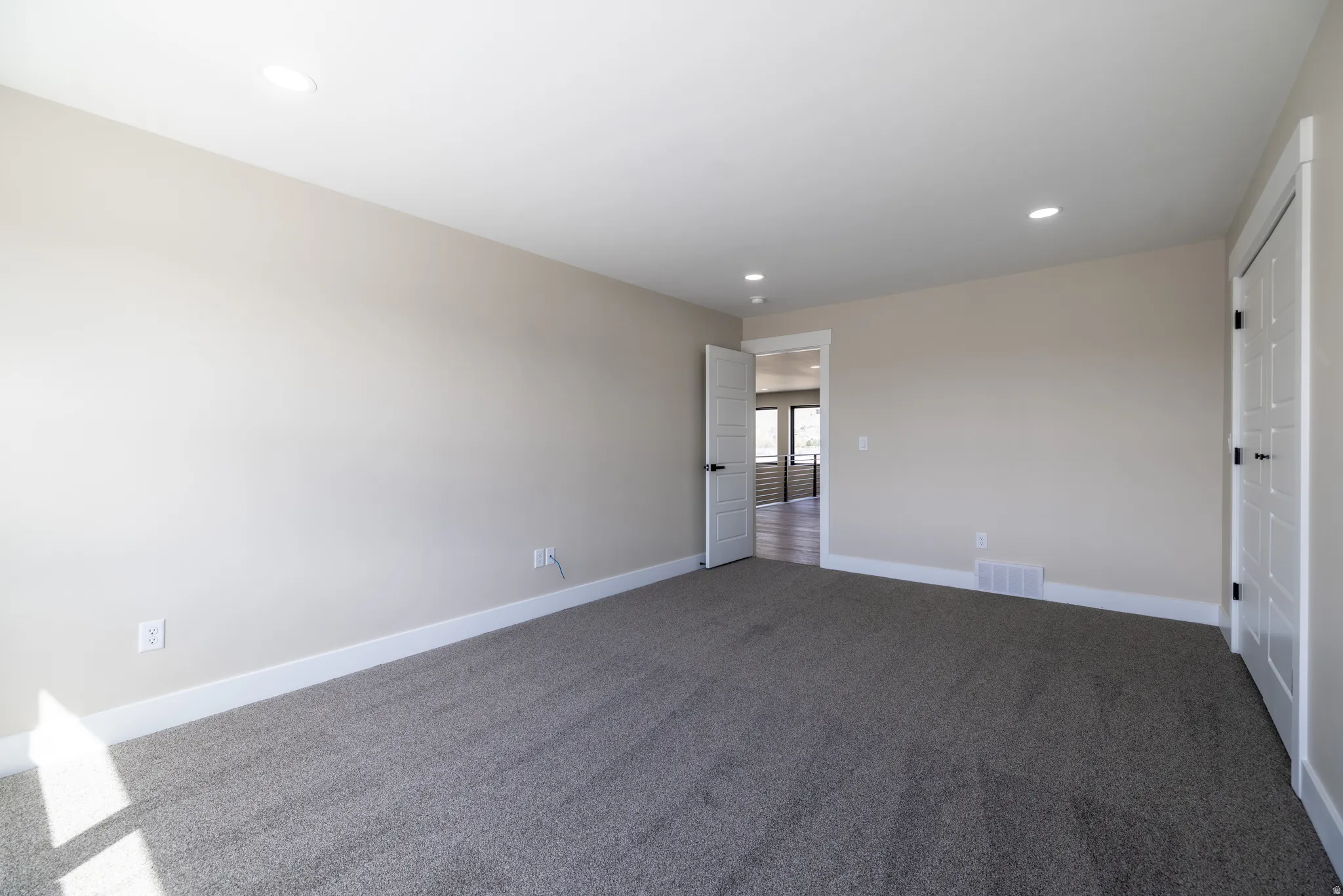 Neutral tone walls, grey carpet flooring, recessed ceiling lighting, and white paneled doors