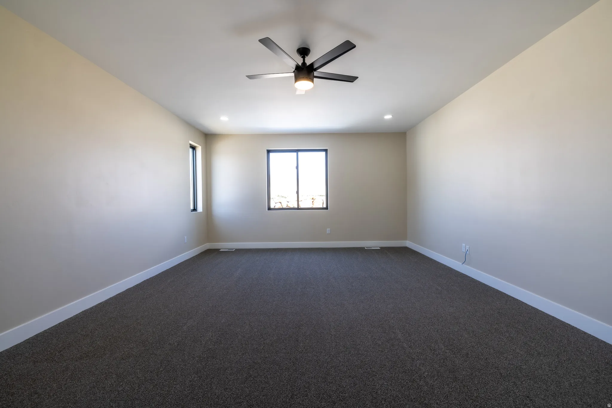 Recessed lighting, ceiling fan, dark carpet flooring, multiple windows, and white trim