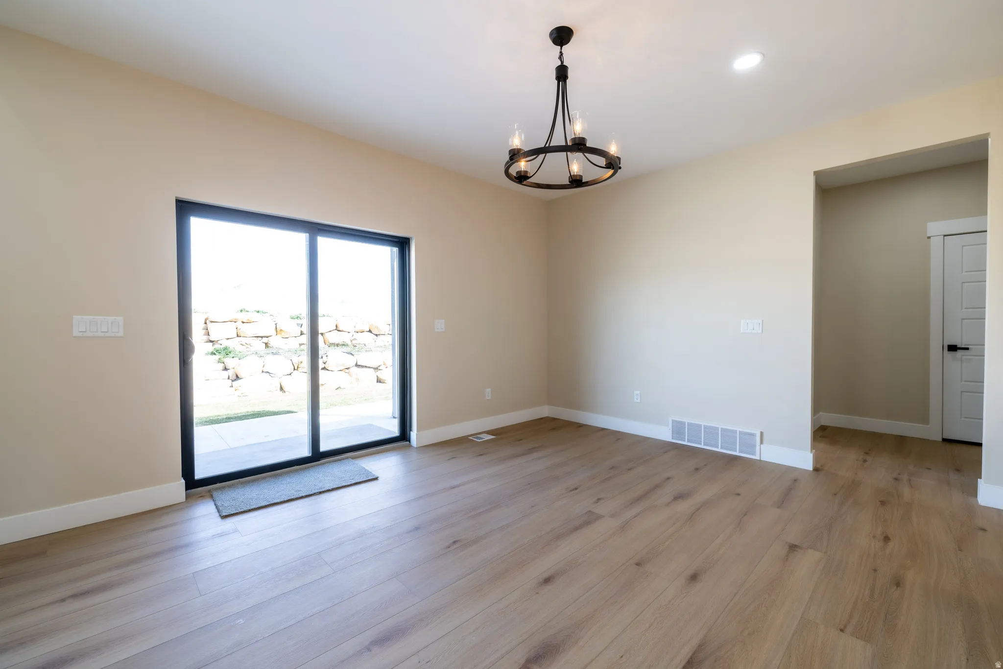 Wood-finish flooring throughout, sliding glass door, recessed lighting, and a black chandelier