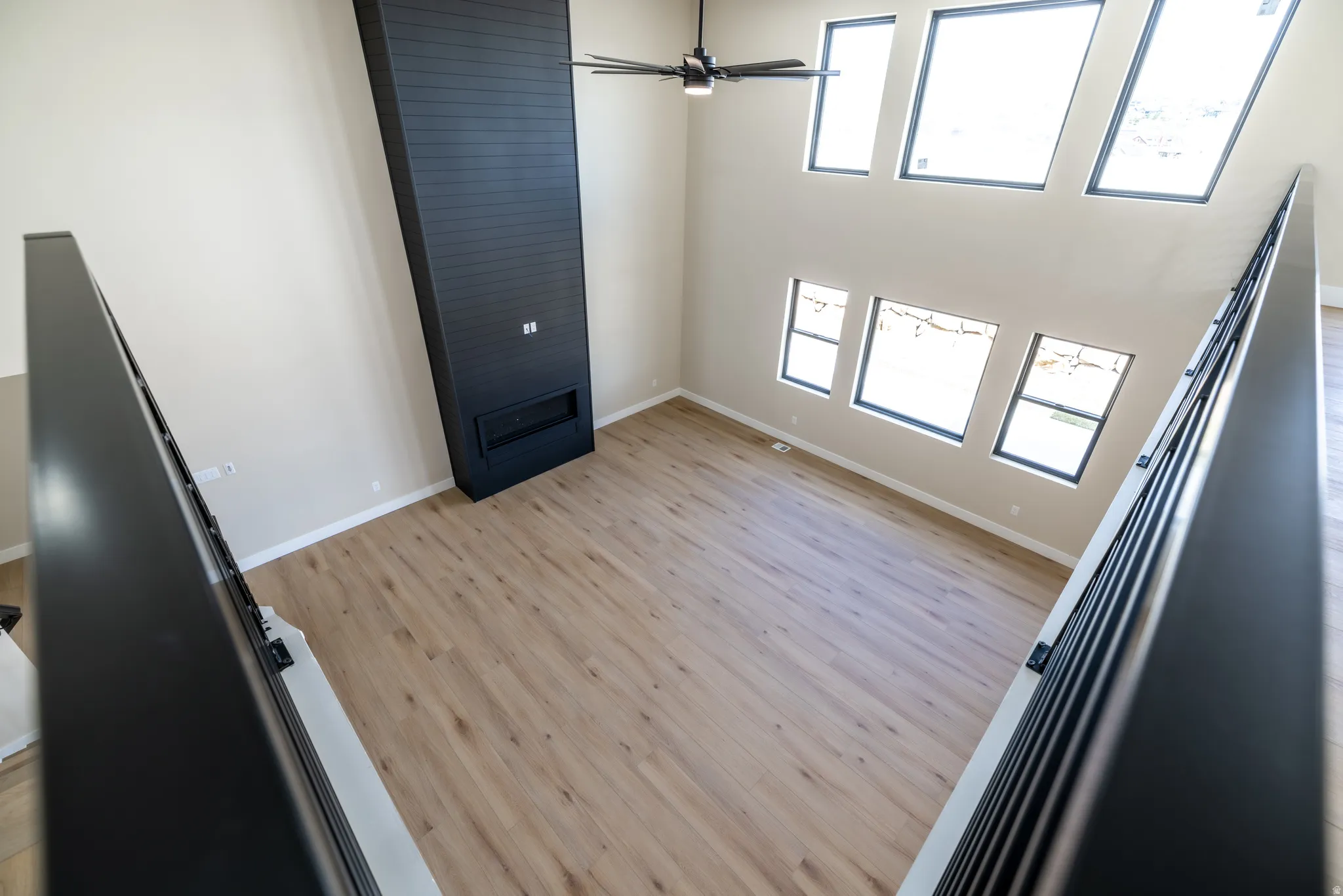 Volume ceiling with a modern black fireplace, wood-finish flooring, and multiple windows