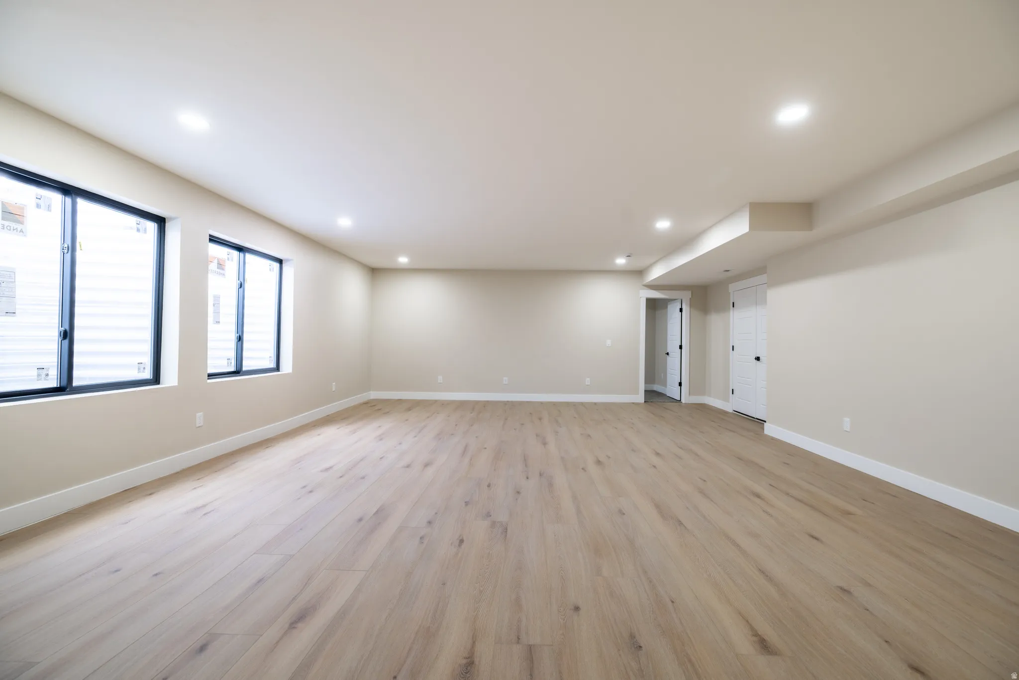 Spacious room featuring wood-finish flooring, recessed lighting, multiple windows, and light-toned walls