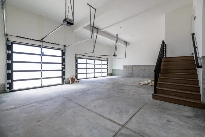 Spacious garage with concrete flooring and multiple overhead doors
