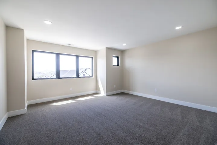 Carpeted room with a multi-pane window, an additional window, and recessed ceiling lighting