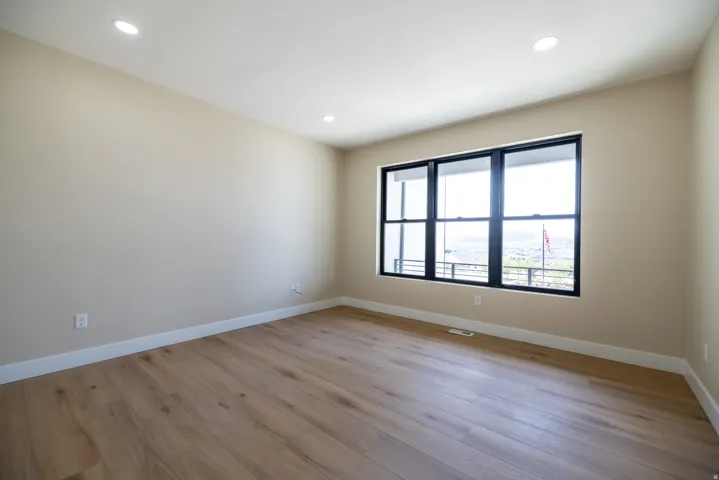 Recessed lighting, light-toned walls, wood-finish flooring, and multi-pane windows with dark frames