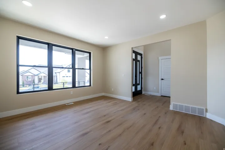 Spacious room featuring wood-finish flooring, recessed lighting, and a large multi-pane window with black framing