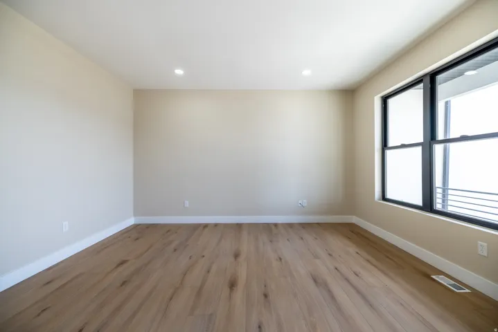 Wood-finish flooring, recessed lighting, and a large window with black framing
