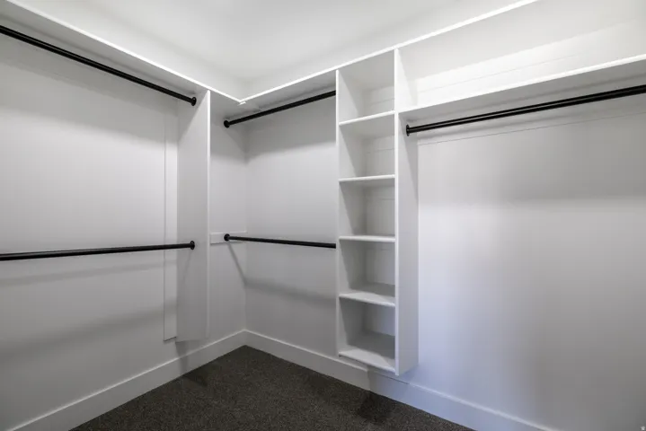 Built-in closet system with multiple hanging rods and open shelving