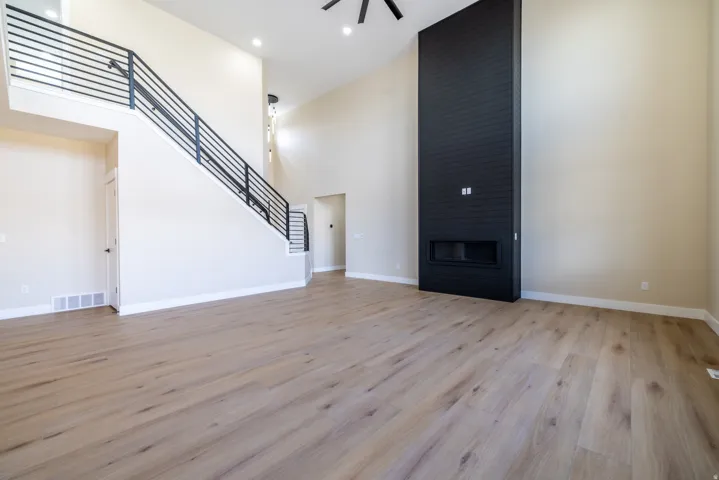Vaulted ceilings, wood-finish flooring, a contemporary black fireplace surround, and modern black stair railings