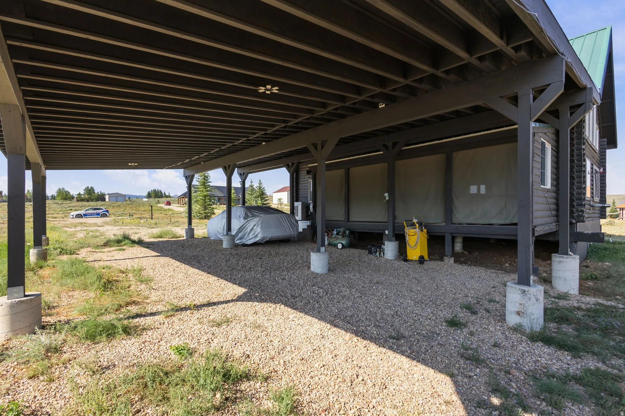 Covered gravel parking area with a wood beam support structure and concrete piers