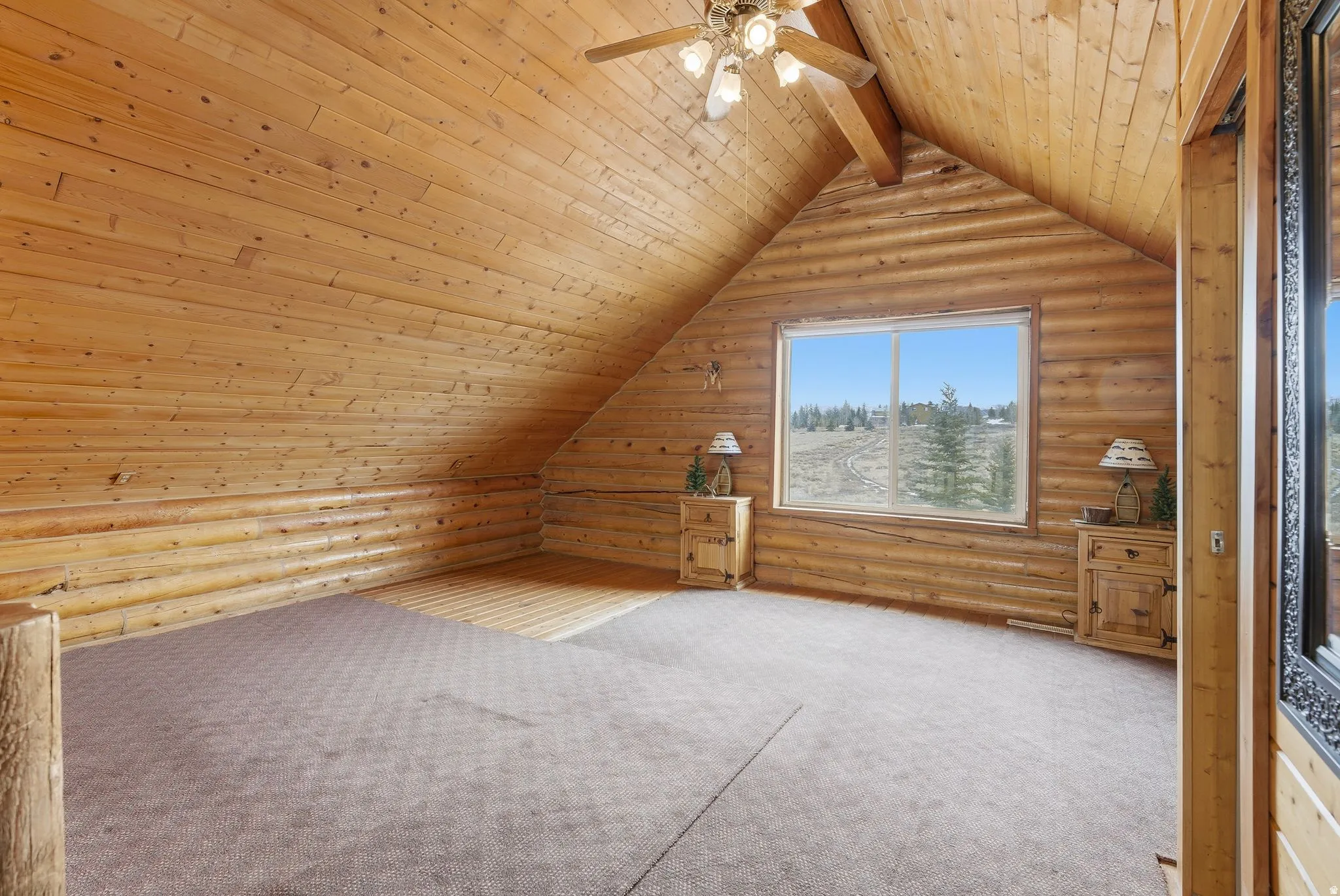 AI RENDERING Vaulted wood-paneled ceiling, exposed wood beams, window with expansive outdoor scenery, wood-finish walls, and ceiling fan