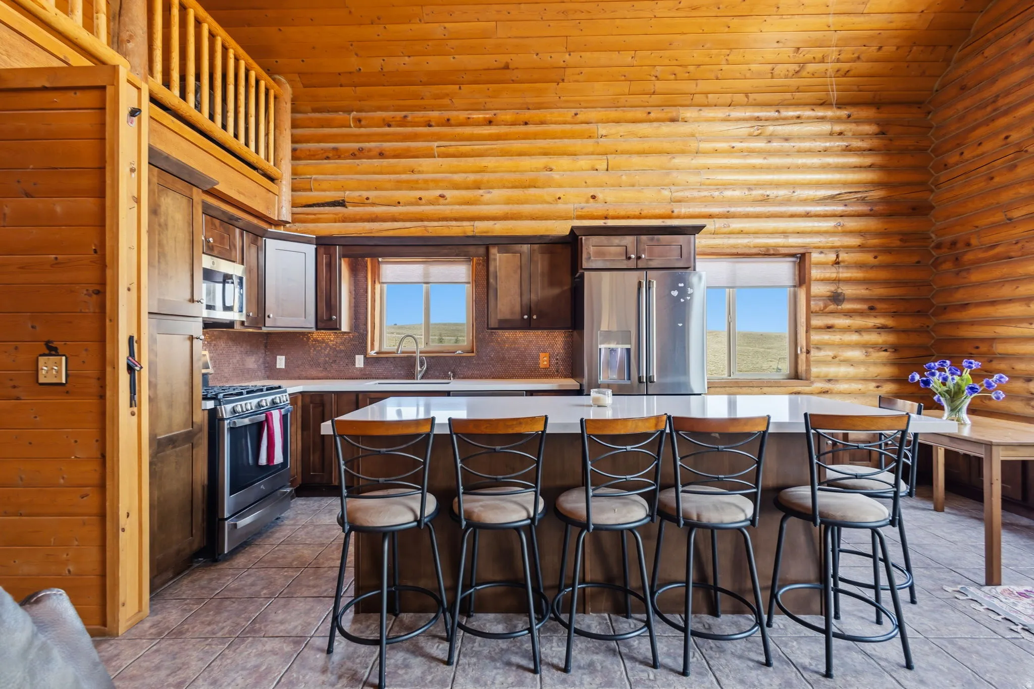 Log construction with wood paneling, stainless steel appliances, solid surface countertops, and an integrated kitchen island