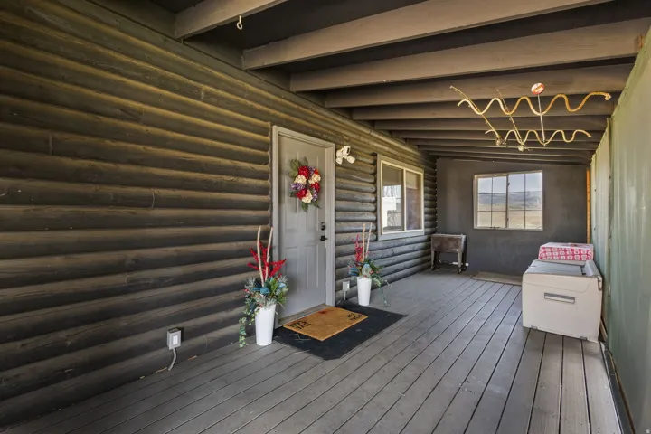 Covered porch featuring a wood-finish floor and log siding