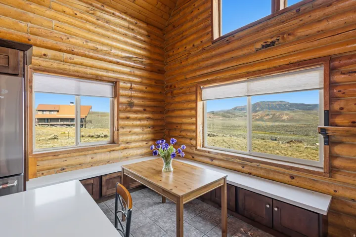 Log wall construction with multiple windows, built-in bench seating, and wood-finish flooring
