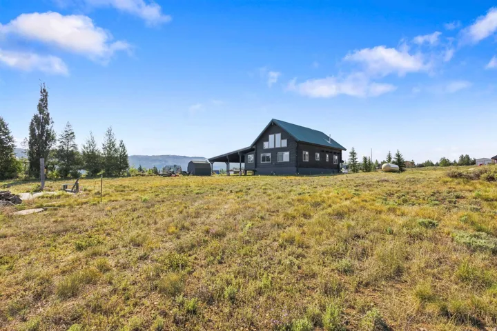 Expansive property with a modern cabin-style residence featuring multiple windows and a covered outdoor area