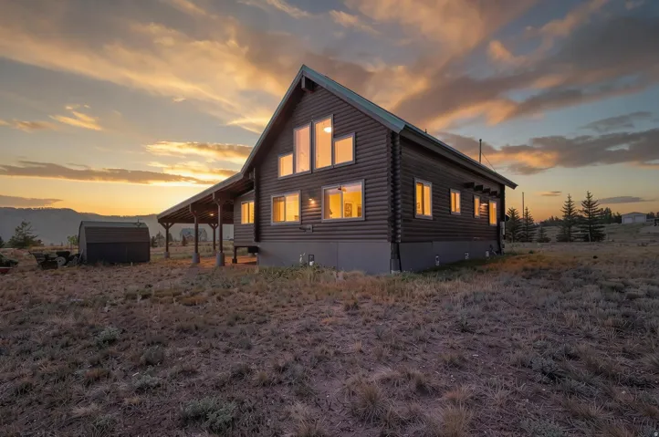 Log cabin exterior with a metal roof and an extended covered porch